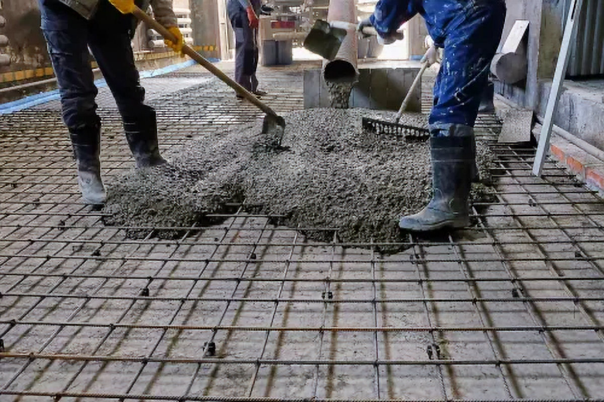 Equipe espalhando concreto sobre tela de aço