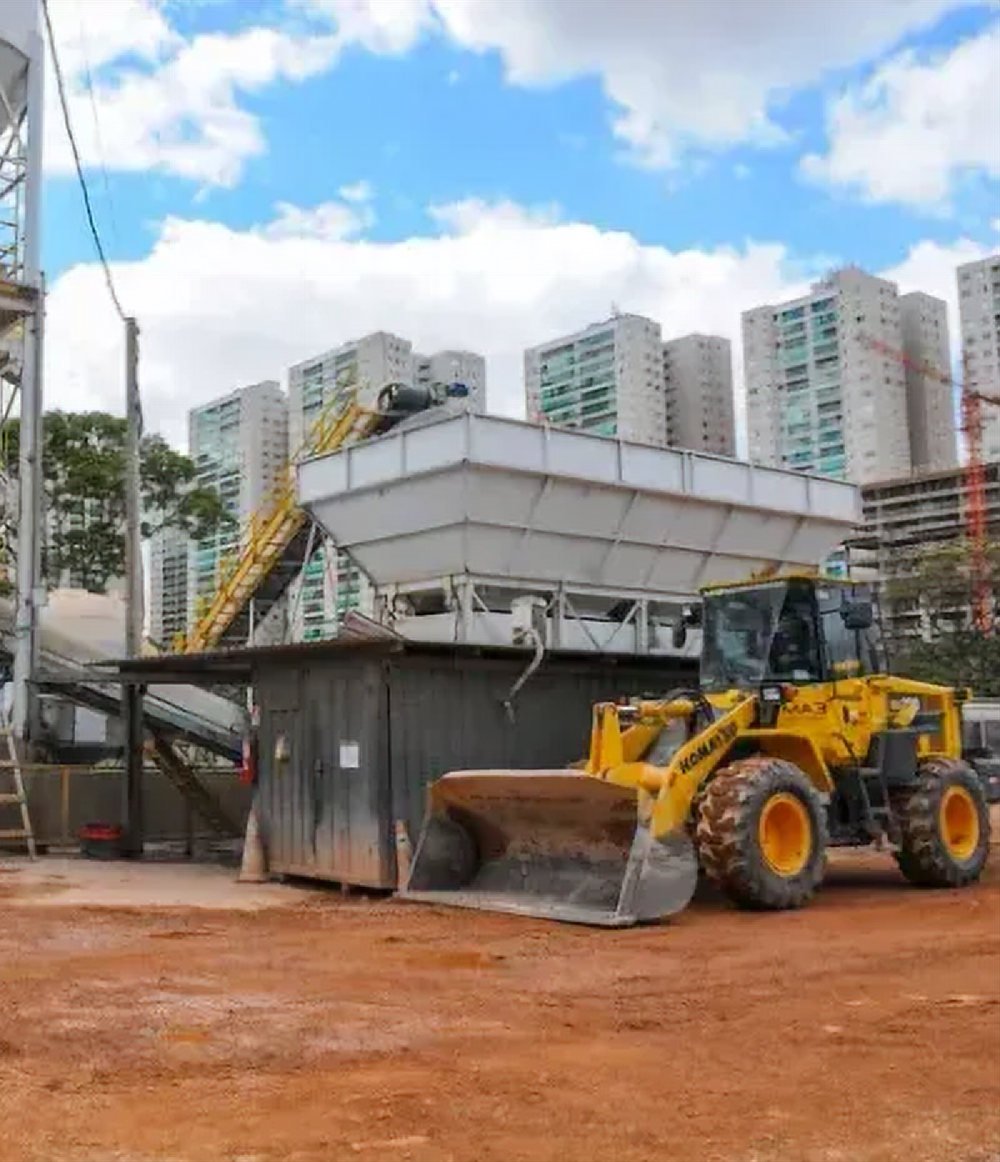 Central de concreto com pá carregadeira abastecendo os agregados